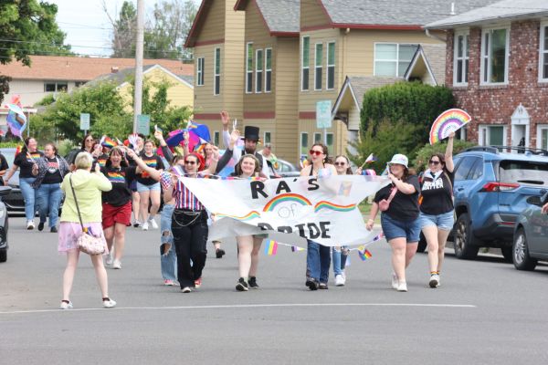 Group of people in a waling parade holding a Pride banner